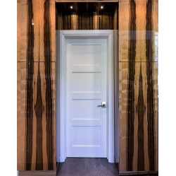 Limbas finierējuma sienu paneļu fonā izceļas baltas krāsotas iekšdurvis.